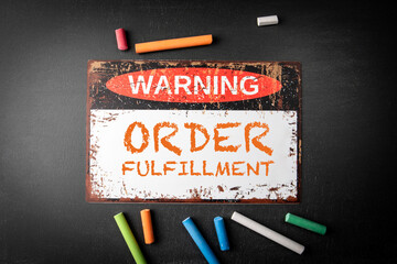 Order fulfillment. Metal warning sign and colored pieces of chalk on a dark chalkboard background - 790980852