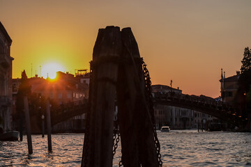 Silhouette of wooden pole and bridge during the sunset over Grand Canal in Venice, Veneto, Italy,...
