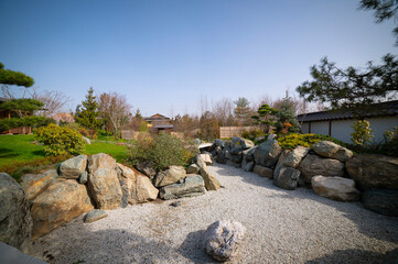 The stones are arranged to form a pond shape.	
A kareike style dry pond in a Japanese garden in a public park. Spring beautiful plant landscape.
