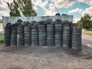 Neatly arranged pile of worn-out tires in various sizes stacked up in an organized manner outdoors...