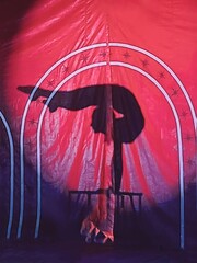 Daring and Skilled Acrobat Silhouette Performing a Spectacular Contortion Act on the Table  isolated in the  Vibrant Red Background. Mesmerizing Circus Show Full of Energy and Excitement