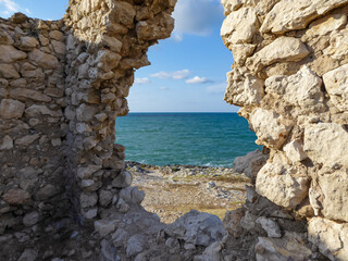 Scenic view through a stone wall of the ruins of ancient watchtower along the Gargano Coast, Apulia, Italy, Europe. Summer on Mediterranean Adriatic sea. Defense towers aigainst Turkish ships
