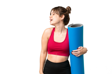 Young sport girl going to yoga classes while holding a mat over isolated chroma key background laughing in lateral position