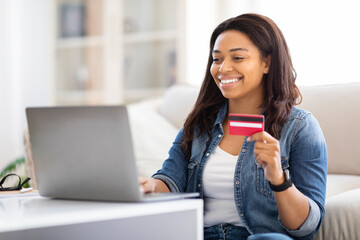Woman Sitting on Couch Holding Credit Card and Laptop, Shopping - obrazy, fototapety, plakaty