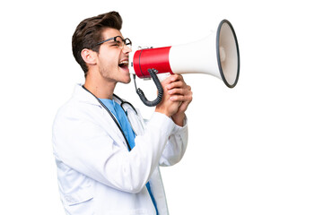 Young doctor man over isolated background shouting through a megaphone