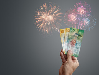 Man holding swiss franc banknotes with fireworks showing a good investment and success