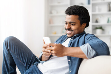 Happy black man using smartphone at home