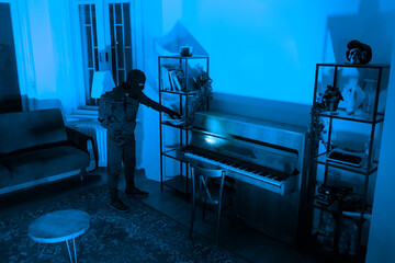 Silhouette of burglar at a piano in a blue room