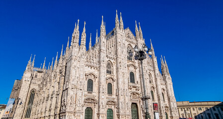 Fototapeta premium External view of Milan Cathedral (Duomo di Milano) from the Piazza del Duomo, Milan, Lombardy, Italy, Europe. Historical marble facade with spires. Gothic architecture features. City travel tourism