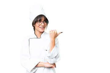Young caucasian chef  woman over isolated chroma key background pointing to the side to present a product