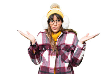 Young caucasian woman wearing winter muffs over isolated chroma key background having doubts while...