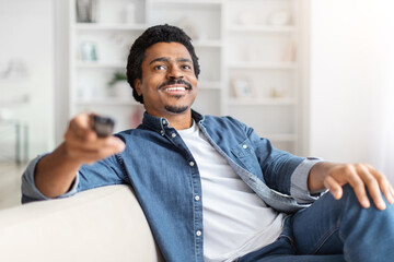 Man smiling holding remote control at home