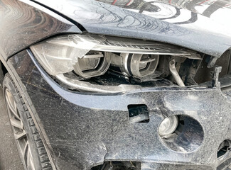 The front part and the headlight of the black car were damaged as a result of a traffic accident....