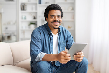 Smiling man holding a tablet at home