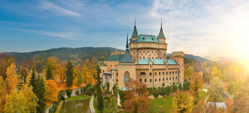 Aerial View of Bojnice Castle in a Neo-Gothic Romantic style against sunset. UNESCO Heritage, Slovakia. Panoramic picture, orange-yellow-green colors, Autumn, blue sky.