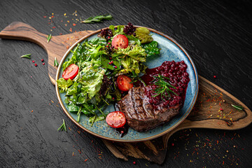 Juicy medium rare beef steak with cranberry sauce. Menu for a pub on a dark background. Colorful juicy food photography.