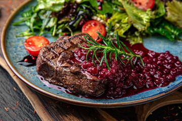 Juicy medium rare beef steak with cranberry sauce. Menu for a pub on a dark background. Colorful juicy food photography.