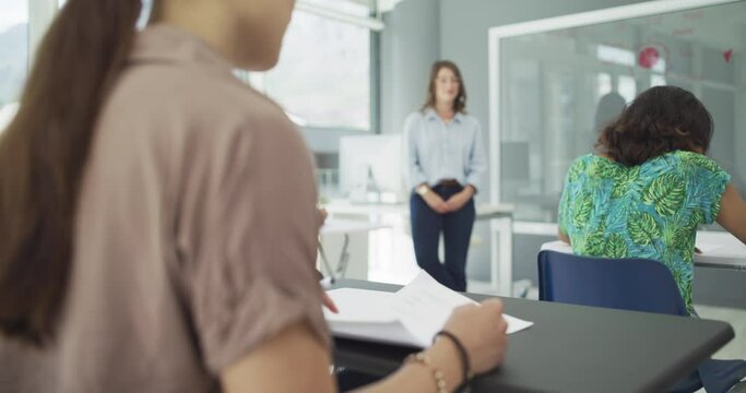 Students, exam and lecturer in classroom with focus, knowledge test and concentration in university. People, diversity and college for learning or education, question paper and moderator on campus