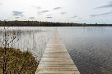 Wooden footbridge in Riebinu (Riebiņu) lake in April in spring in Latvia
