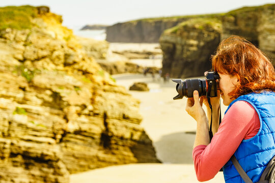 Woman with camera at Cathedral Beach in Spain.
