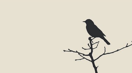 Naklejka premium A black bird atop a tree branch against a light backdrop
