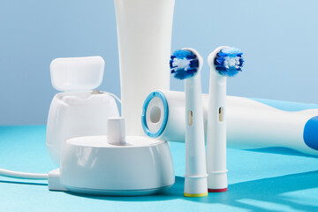 Electric toothbrush with contactless charging and oral hygiene products on pastel background.Oral...