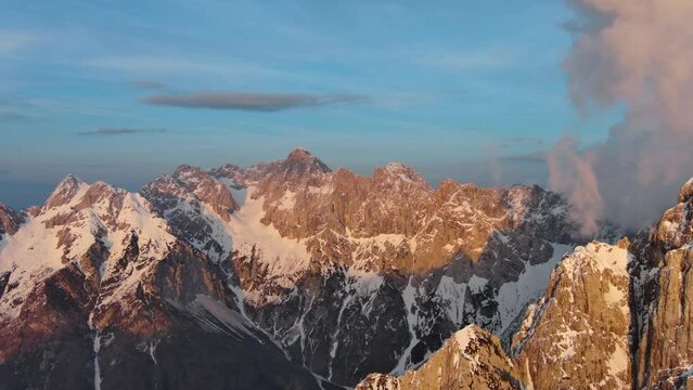 Aerial view of high mountains and clouds in the Triglav National Park at sunset, Julian Alps, Slovenia, panorama 4k