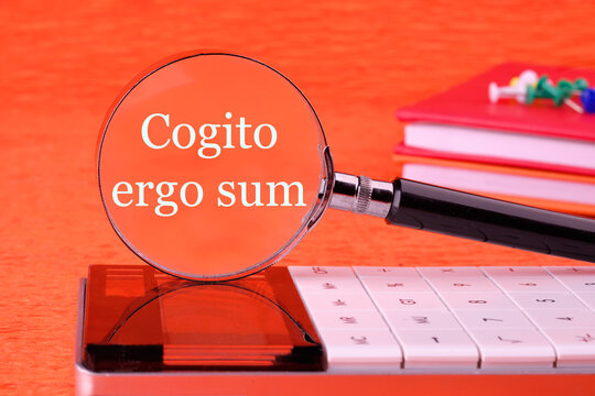 The words Cogito Ergo Sum or I think Therefore I Am through a magnifying glass in white font on an orange background