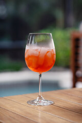 Fun orange summer cocktail by the pool, verticle