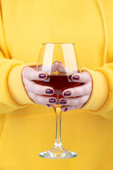 Female hands with fashionable manicure holding a glass of red wine.