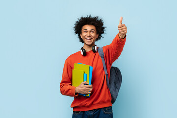 Positive student with books showing thumbs up