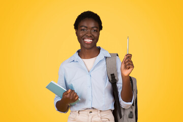 Happy african american woman student pointing upwards