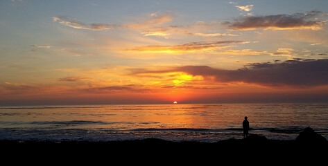 a man standing on top of a beach next to the ocean