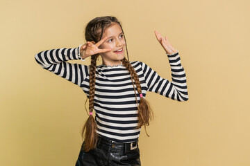 Happy smiling young preteen child girl kid listening music, dancing disco, fooling around having fun expressive gesticulating hands relaxing on party, making funny moves. Children on beige background
