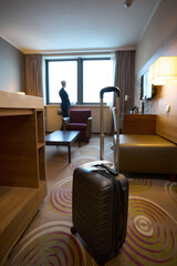 Focus on suitcase with blurred businesswoman standing and looking from window
