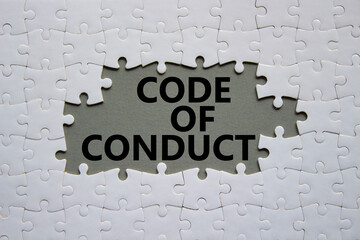 Code of conduct symbol. White Puzzle with words Code of conduct. Beautiful grey background. Business and Code of conduct concept. Copy space.