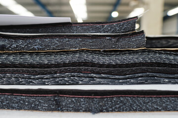 A pile of raw denim sheets fresh off a production line in a denim factory. Industrial fabric and...