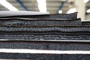 A pile of raw denim sheets fresh off a production line in a denim factory. Industrial fabric and...