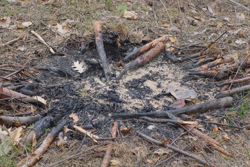 an extinct fire made of black ash and ash on the brown ground on the street