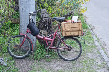one old red bicycle with a black bag on the steering wheel and a wooden box on the trunk stands by...