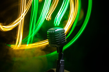 Microphone for sound, music, karaoke in audio studio or stage. Mic technology. Speech broadcast equipment. Microphone in dark room on table with backlight. Selective focus