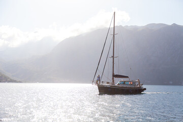 Yacht sailing at sea. Traveling with amazing view and landscape, beautiful nature, mountains, coast. Travelers enjoying summer vacation. People have fun and adventure. Tourism on wooden sailboat