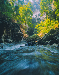 In the tropical forest of Kanchanaburi, Thailand's national park, waterfall flows pass the rock...