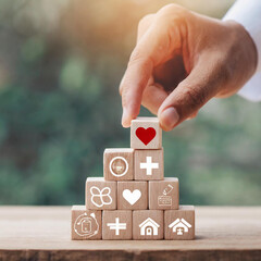 Health Insurance Concept, Hand arranging wood cube stacking with icon healthcare medical on wood background, copy space, financial concept.