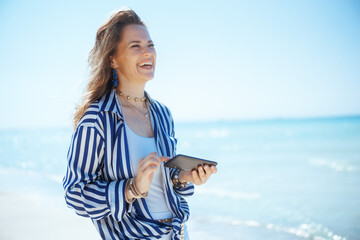 happy elegant female on seashore with smartphone