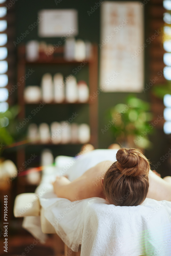 Poster relaxed modern woman in spa salon laying on massage table