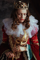 pensive medieval queen in red dress with venetian mask
