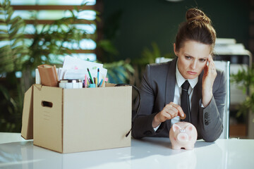 woman worker in green office putting coin into piggy bank