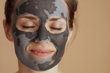 relaxed young woman with cosmetic mask isolated on beige