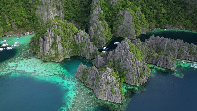 Aerial view of tropical island. Boats in blue lagoons, rocks cliffs mountains and coral reef, Philippines, 4k
